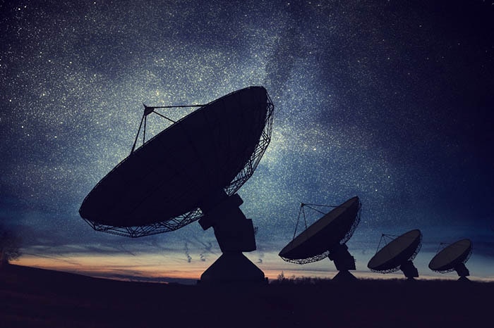 Silhouettes of satellite dishes or radio antennas against night sky. Kuvituskuva: CGI - avaruusteknologian asiantuntija Suomessa