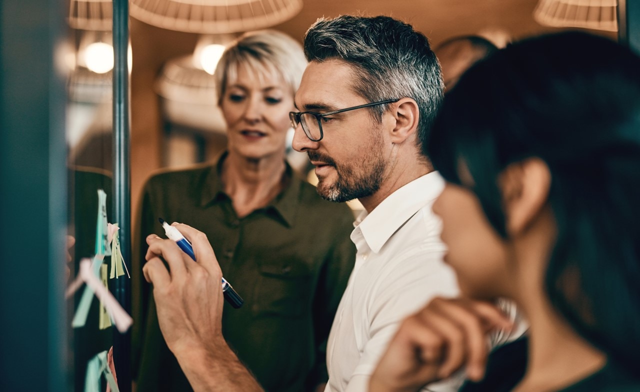 Colleagues discussing application modernization on a whiteboard Colleagues discussing application modernization on a whiteboard