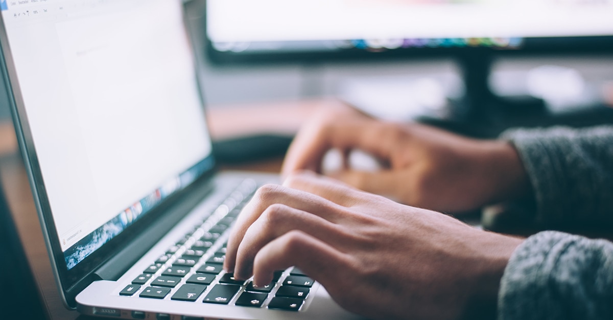 computer-rpa Händerna på en man som sitter och knappar på en laptops tangentbord.