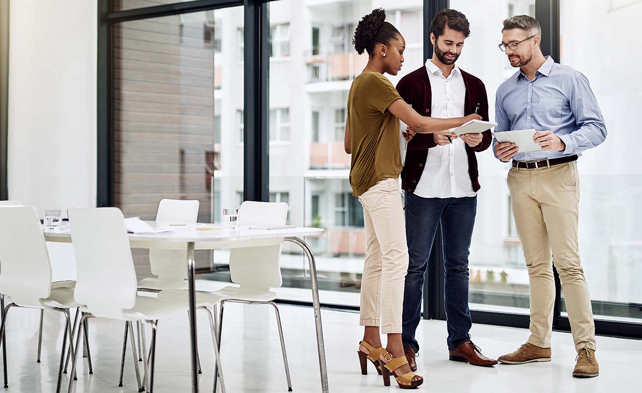 three advisory consultants discussing business while standing three advisory consultants discussing business while standing