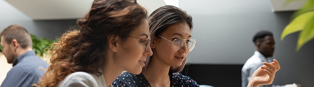 Innovations coach medium mobile Två kvinnor sitter framför en laptop i öppet kontorslandskap