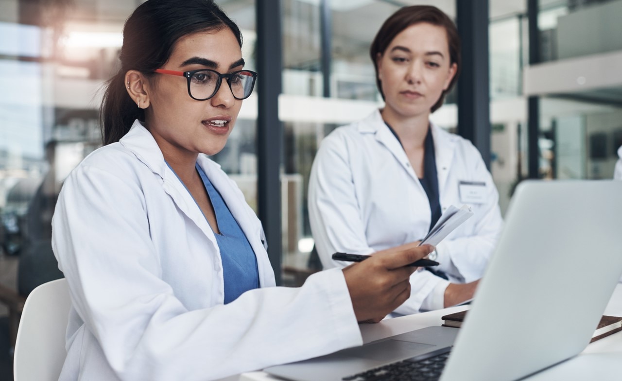 Medical professionals discussing information displayed on a laptop Medical professionals discussing information displayed on a laptop