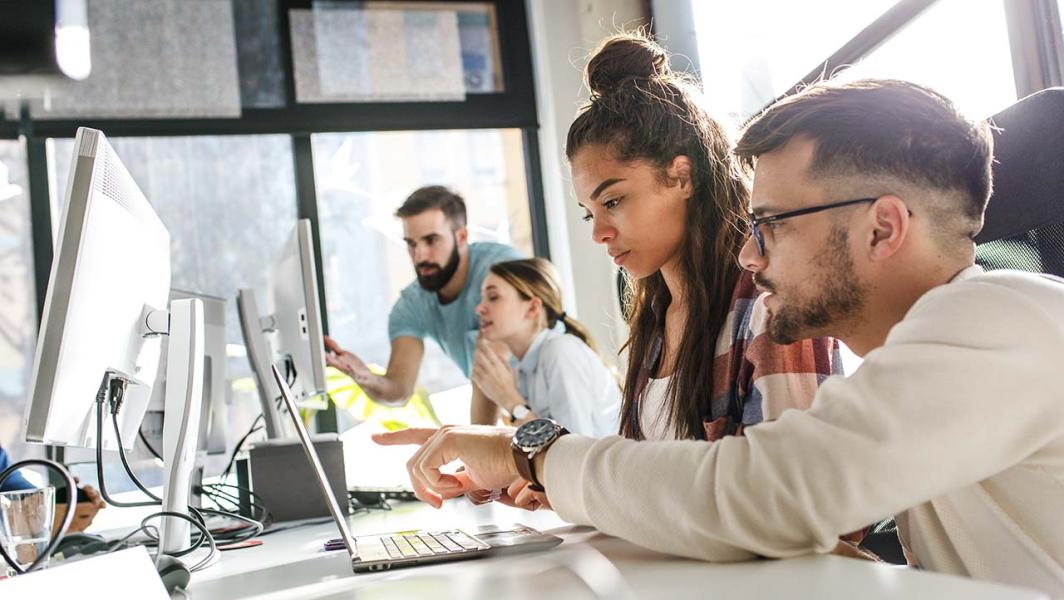 Co-workers working and talking in front of computer screens Co-workers working and talking in front of computer screens