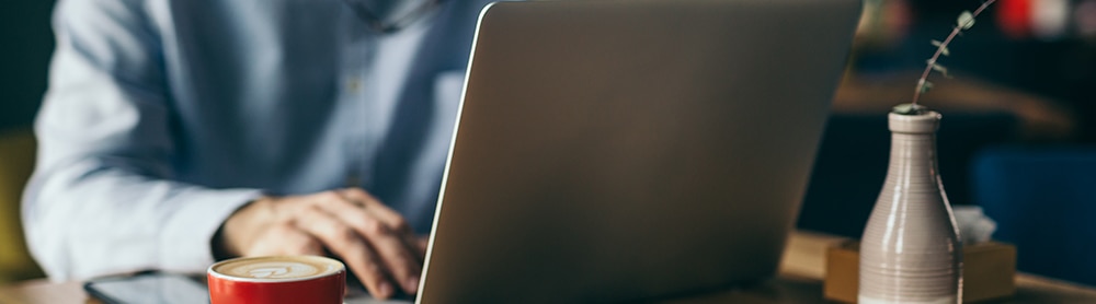 Professional working on laptop with a cup of coffee Professional working on laptop with a cup of coffee