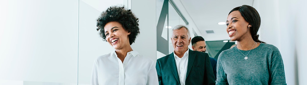 Group of professionals, two females and one male walking along office corridor Group of professionals, two females and one male walking along office corridor