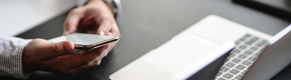 CGI Trade360 Portal Person holding a phone next to office hardware