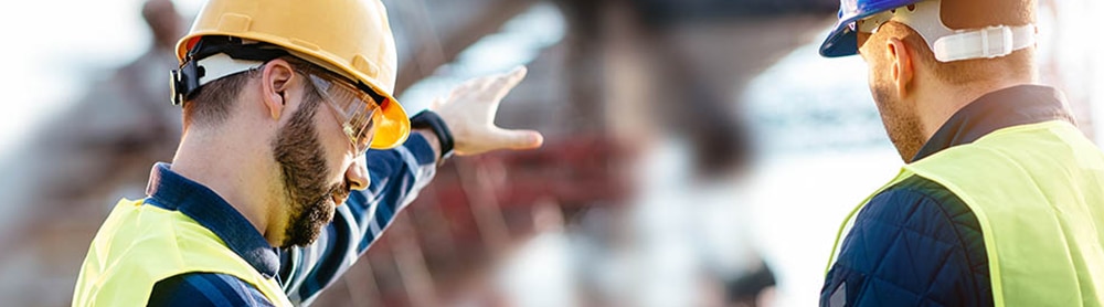 Workers looking at stats and diagrams on clipboard Workers looking at stats and diagrams on clipboard