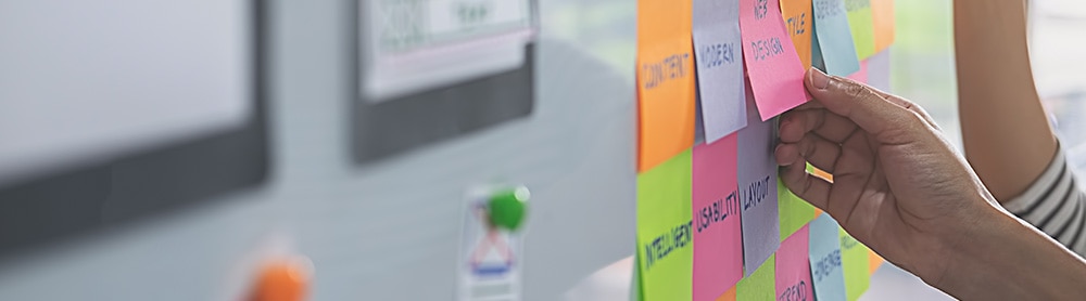 Person placing post its on a board Person placing post its on a board