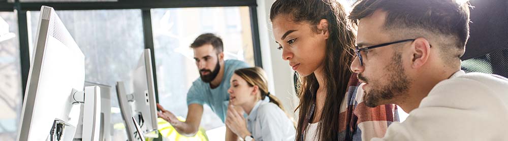 Co-workers working and talking in front of computer screens Co-workers working and talking in front of computer screens