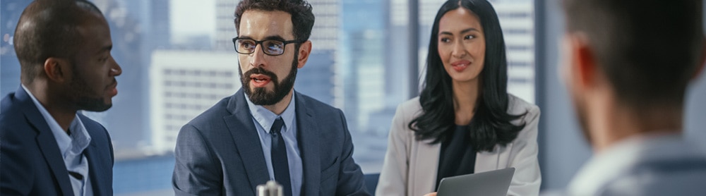 four consultants sit in discussion around an office table four consultants sit in discussion around an office table
