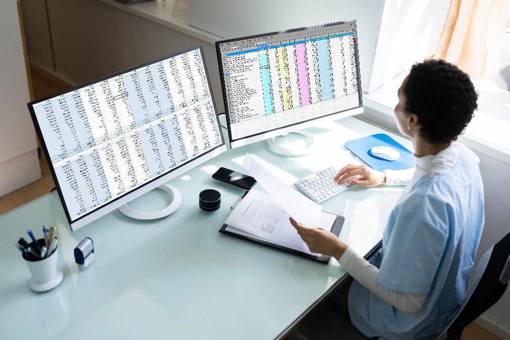 Professional reviewing data on two monitors