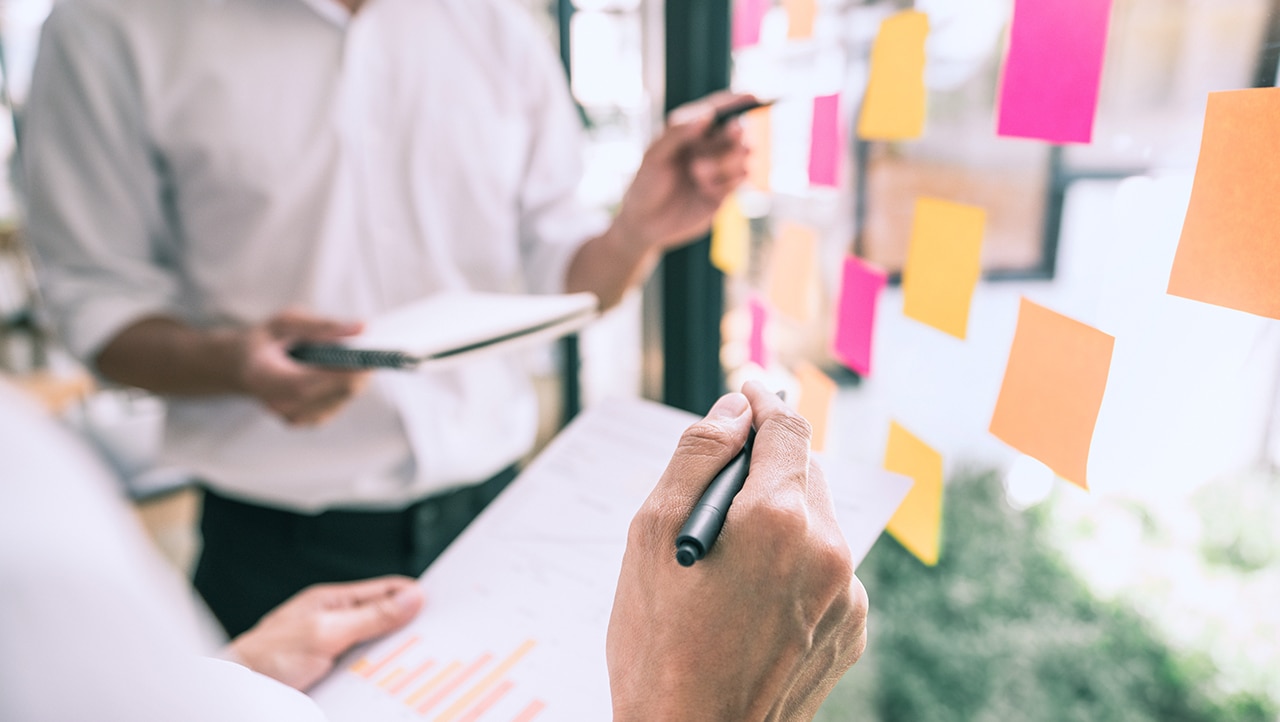 People organizing sticky notes on window for RCDA