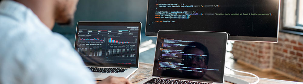 Software engineer coding on multiple screens - Application Services Software engineer coding on multiple screens - Application Services