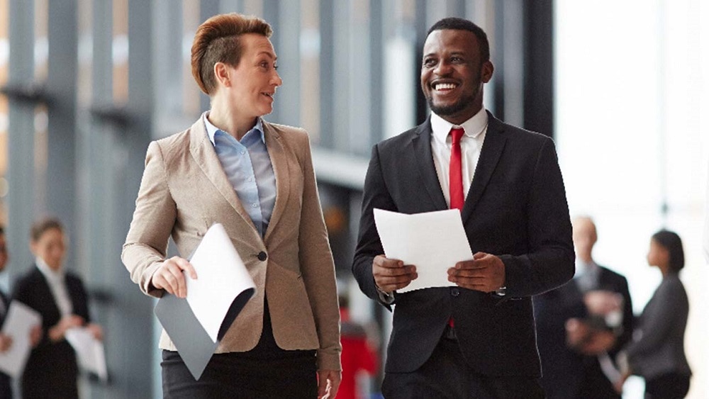Two colleagues smiling while walking Two colleagues smiling while walking