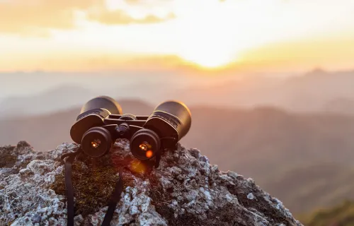 Binoculars on a rock overlooking mountains