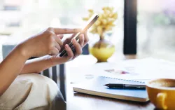 Person sitting at table, holding mobile phone