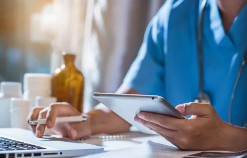 health professional using a laptop and tablet