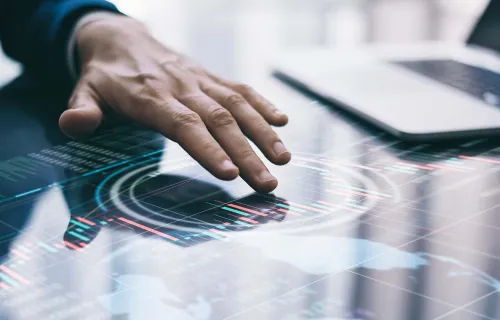 a hand using a digital interface with laptop in the background