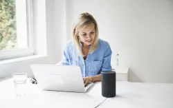 consultant working on a laptop next to a smart speaker