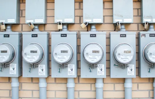 Rekke med strømmålere på vegg – illustrerer datainnsamling og automatisering i digitale…