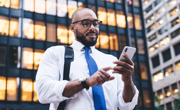 Person standing outside a building with smartphone