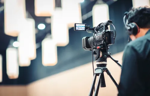 Person wearing headphones standing behind camera
