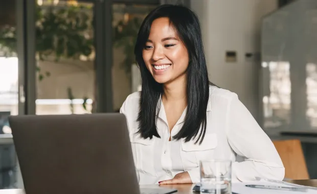 person smiling while working on a laptop