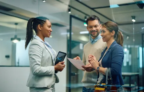Three professionals in a modern office discussing a document 
