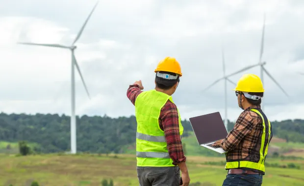 Ingénieurs effectuant des relevés d'éoliennes tout en tenant un ordinateur portable